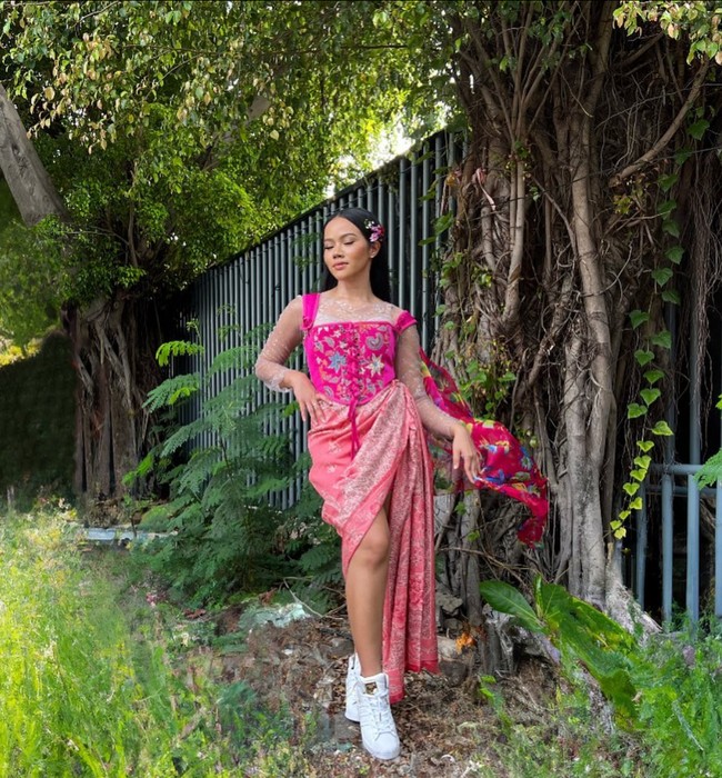 Kebaya pun bisa tampil playful dan girlie jika Yura Yunita yang memakainya. Penyanyi jebolan Indonesian Idol ini memadukan blouse tanpa lengan warna fuchsia berhias bordir dengan dalaman transparan dan kain batik bernuansa pink. Sneakers memberi kesan sporty dan casual pada kebaya. Foto: Instagram/@yurayunita