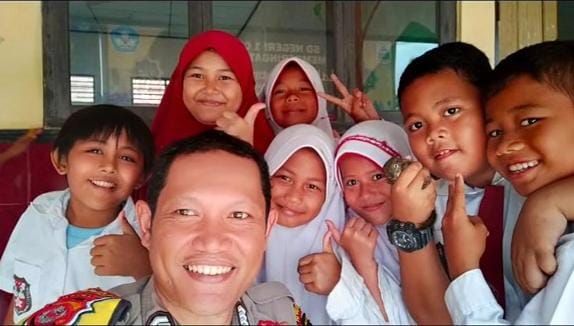 Bripka Okky Kurniawan bersama anak-anak sekolah di Lebak.