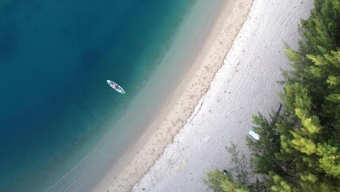 Foto aerial panorama pantai objek wisata Villa Kencana di Botumoito, Kabupaten Boalemo, Gorontalo, Senin (6/3/2023). Villa Kencana menjadi destinasi wisata pantai baru di Gorontalo yang menyajikan keindahan alam, pasir putih, pohon pinus dan fasilitas pendukung wisata seperti wahana perahu kayak, speed boat dan penginapan bagi wisatawan. ANTARA FOTO/Adiwinata Solihin/YU