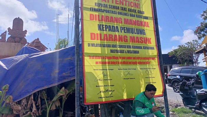 Potret pengemudi ojol beristirahat di bawah baliho 