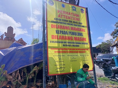 Potret pengemudi ojol beristirahat di bawah baliho Ojol Dilarang Mangkal di Canggu, Badung, Selasa (7/3/2023).