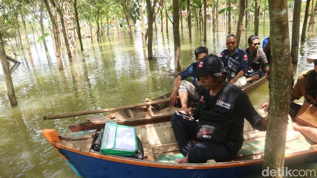 Petugas pantarlih di Pati menggunakan perahu untuk melakukan coklit ke desa-desa yang dilanda banjir, Selasa (7/3/2023).