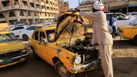 Seorang pengemudi taksi melihat mesin mobilnya saat menunggu penumpang di Stasiun Taksi General Khartoum di Khartoum, Sudan, Minggu (26/2/2023).  