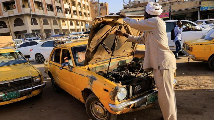 Potret Taksi Kuning Sudan yang Tergerus Zaman A taxi driver rests inside a car as he waits for clients at the General Khartoum Taxi Station in Khartoum, Sudan February 26, 2023. REUTERS/Mohamed Nureldin Abdallah