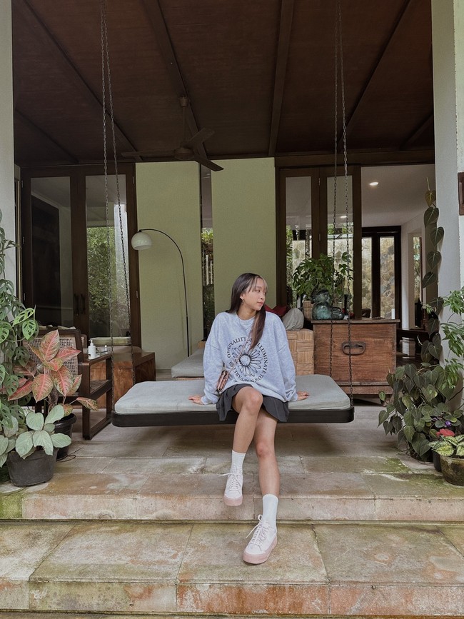 Foto tersebut dibagikan Dita Karang pada Kamis (2/2/2023) lewat Weverse. Terlihat ada tempat bersantai di luar rumahnya yang didominasi ornamen kayu. Dia duduk di atas ayunan sambil menunjukkan gaya berpakaiannya hari itu. Foto: Instagram