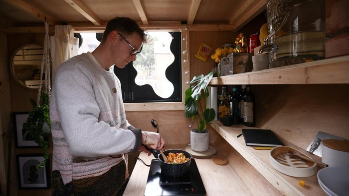 Artist Harrison Marshall poses inside the skip which he has converted into a home, where he intends to live in for a year, in Bermondsey, London, Britain, March 3, 2023. REUTERS/Henry Nicholls
