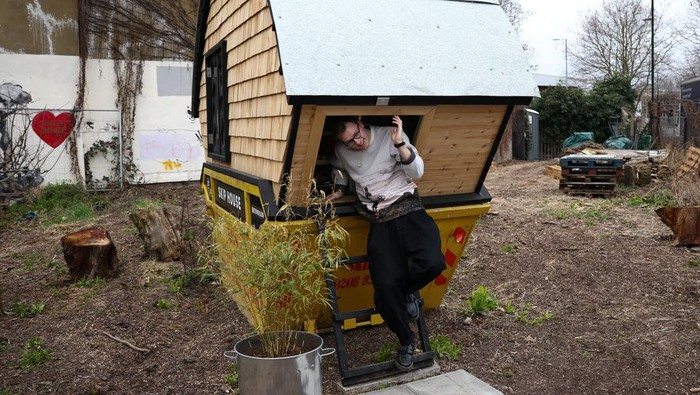 Artist Harrison Marshall poses inside the skip which he has converted into a home, where he intends to live in for a year, in Bermondsey, London, Britain, March 3, 2023. REUTERS/Henry Nicholls