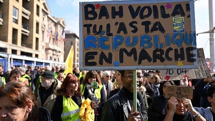 People take part in a demonstration in Marseille on March 7, 2023, as part of a nationwide day of strikes and protests called by unions over the proposed pensions overhaul, which include raising the minimum retirement age to 64 from 62 and increasing the number of years people have to make contributions for a full pension. - The banner reads in French 