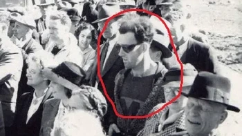 Foto ini diambil pada tahun 1941 saat pembukaan kembali South Forks Bridge di Kanada. Sekilas terlihat seperti gambar lain dari periode waktu itu… Tetapi jika Anda memeriksa detailnya, ada sesuatu yang tidak beres. Tampaknya ada satu pria berpakaian modern di antara topi dan jas tahun 1940-an. Dia juga tampaknya memegang kamera modern, memakai kacamata aneh dan memakai logo yang tidak sesuai dengan periode waktunya. Foto: Reddit