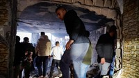 Tampak warga Palestina berkumpul di sebuah rumah yang hancur setelah diserang pasukan Israel.