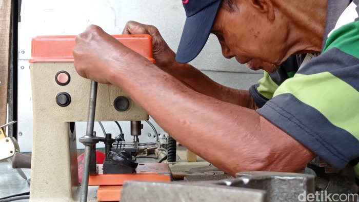 Lili tengah tekun bekerja membuat kunci duplikat.
