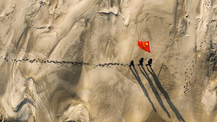 ALTAY, CHINA - MARCH 07: Policemen holding a Chinese national flag patrol the desert area on March 7, 2023 in Altay Prefecture, Xinjiang Uygur Autonomous Region of China. (Photo by VCG/VCG via Getty Images)