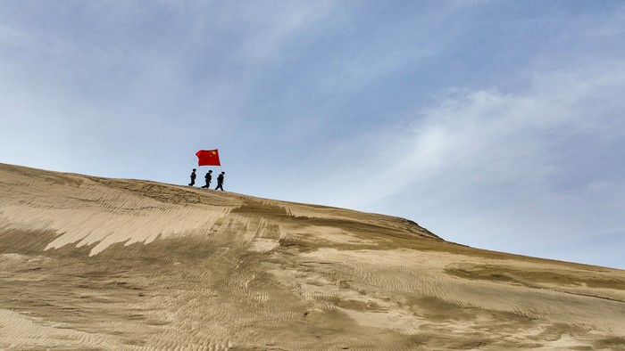 ALTAY, CHINA - MARCH 07: Policemen holding a Chinese national flag patrol the desert area on March 7, 2023 in Altay Prefecture, Xinjiang Uygur Autonomous Region of China. (Photo by VCG/VCG via Getty Images)