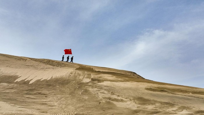 ALTAY, CHINA - MARCH 07: Policemen holding a Chinese national flag patrol the desert area on March 7, 2023 in Altay Prefecture, Xinjiang Uygur Autonomous Region of China. (Photo by VCG/VCG via Getty Images)