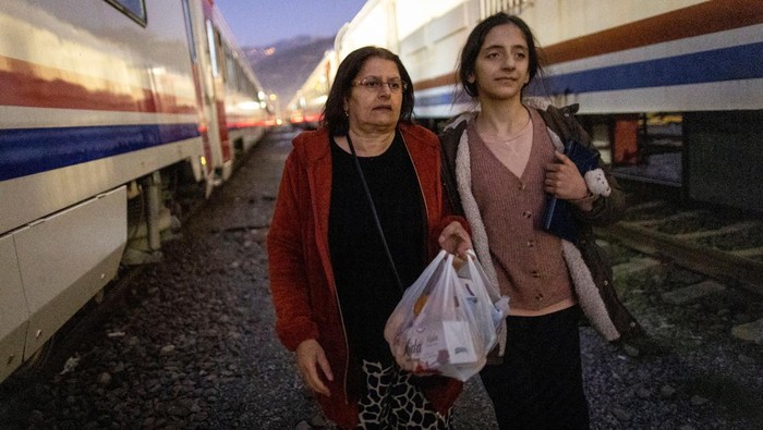 Potret Korban Gempa Turki Berlindung di Kereta Api Sabriye Karan, 57, and her daughter Nehir Karan, 13, walk on the tracks at Iskenderun train station, where train carriages have been turned into temporary shelters for victims of the recent deadly earthquake, after receiving food aid in Iskenderun, Turkey, February 17, 2023. Their narrow cabin, the width of a train window, holds a few essentials and is warmer in the cold nights than a tent. They spend at least 18 hours a day inside, leaving only to take short walks around the station and line up for breakfast and dinner served by aid groups. REUTERS/Eloisa Lopez SEARCH