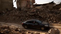 Warga yang melintas dengan mobil, menggunakan ponselnya untuk merekam puing-puing pasca gempa mematikan di Antakya. Sementara puluhan ribu orang masih hilang dan ratusan ribu orang kehilangan tempat tinggal.