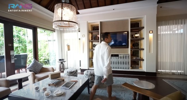 Ruang keluarga di villa tersebut tampak luas dan nyaman dilengkapi dengan sofa dan televisi. Untuk menambah keindahan, pada bagian tengah di atas mejanya terdapat lampu gantung kristal yang cantik. Foto: YouTube/Rans Entertainment