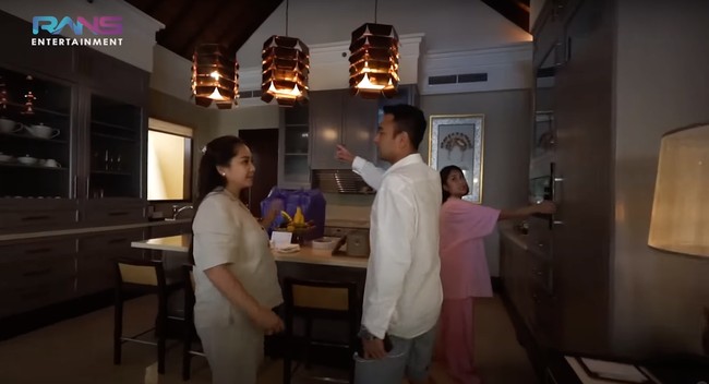 Di sebelah ruang keluarga terdapat dapur yang tak kalah elegan dan mewah. Dilengkapi dengan 3 lampu gantung bernuansa warm, dapur tersebut terlihat cukup lengkap. Terdapat kulkas, kitchen set, kompor, dan peralatan dapur lainnya. Foto: YouTube/Rans Entertainment
