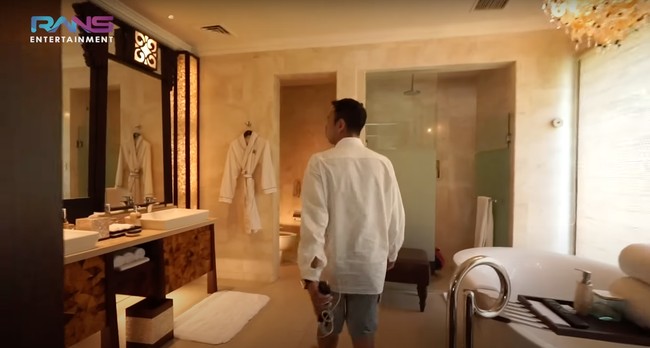 Kalau yang satu ini penampakan kamar mandi di dalam kamar utama villa. Dengan lampu-lampu berwarna kuning, kamar mandi tersebut jadi memancarkan nuansa hangat dan nyaman. Kamar mandi yang cukup luas itu juga dilengkapi dengan bathtub. Foto: YouTube/Rans Entertainment