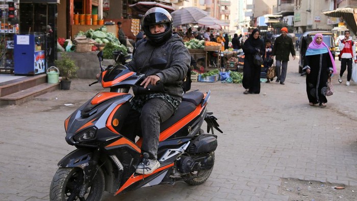 Wanita Ini Buka Jasa Ojek Khusus Perempuan di Mesir Egyptian scooter courier Eman Al-Adawi, 36 years old, wears her helmet as she provides a taxi service for women in the Imbaba district of Giza, Egypt February 21, 2023. Eman succeeded in the last few months and dreams for a new app-based business with an all-woman team including instructors and mechanics, that goes against harassment and a way to face devaluation of the Egyptian pound which affected the economic conditions in the country. REUTERS/Hanaa Habib