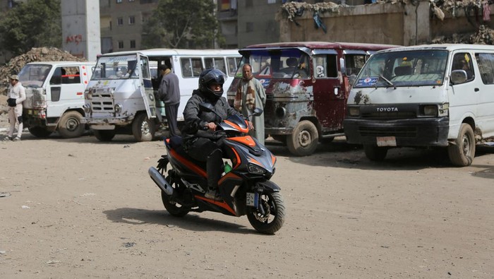 Wanita Ini Buka Jasa Ojek Khusus Perempuan di Mesir Egyptian scooter courier Eman Al-Adawi, 36 years old, wears her helmet as she provides a taxi service for women in the Imbaba district of Giza, Egypt February 21, 2023. Eman succeeded in the last few months and dreams for a new app-based business with an all-woman team including instructors and mechanics, that goes against harassment and a way to face devaluation of the Egyptian pound which affected the economic conditions in the country. REUTERS/Hanaa Habib