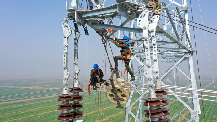 LIANYUNGANG, CHINA - MARCH 09: Employees of Jiangsu Power Transmission and Transformation Co., Ltd. work on a 70-meter-high transmission tower at Tianwan Nuclear Power Plant on March 9, 2023 in Lianyungang, Jiangsu Province of China. (Photo by Shi Jun/VCG via Getty Images)