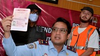 Kepala Kantor Imigrasi Kelas I TPI Denpasar Tedy Riyandi (tengah) menunjukkan paspor milik warga negara Rusia berinisial SR (kanan) yang akan dideportasi saat konferensi pers di Kantor Imigrasi Kelas I TPI Denpasar, Bali.