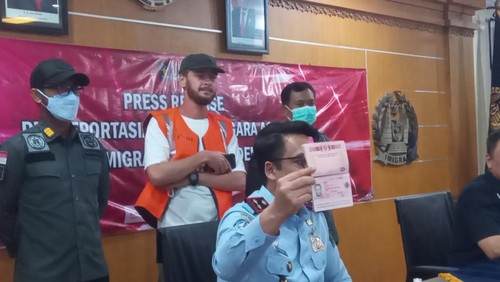 Petugas Imigrasi Denpasar menunjukkan paspor Sergei Rodin saat tertangkap usai kedapatan bekerja secara ilegal sebagai fotografer di Bali, Rabu (8/3/2023).
