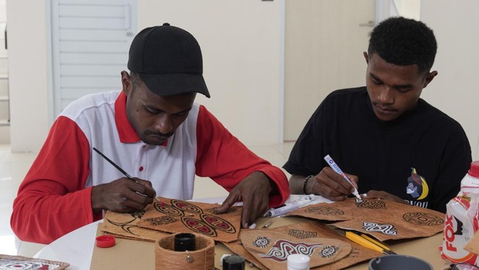 Pemuda Papua membuat kerajinan tangan.