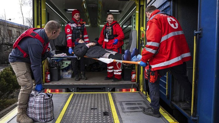 MSF workers carry a man on a stretcher into a MSF medical train that evacuates patients from near the frontline of the fighting to safer areas, at the train station in Pokrovsk, Ukraine, Tuesday, March 7, 2023. (AP Photo/Evgeniy Maloletka)