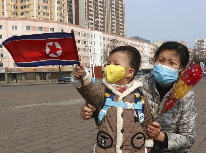 A North Korean woman and her grandson wave a national flag in front of the Pyongyang Grand Threatre as they celebrate International Womens Day in Pyongyang, North Korea, Wednesday, March 8, 2023. (AP Photo/Cha Song Ho)