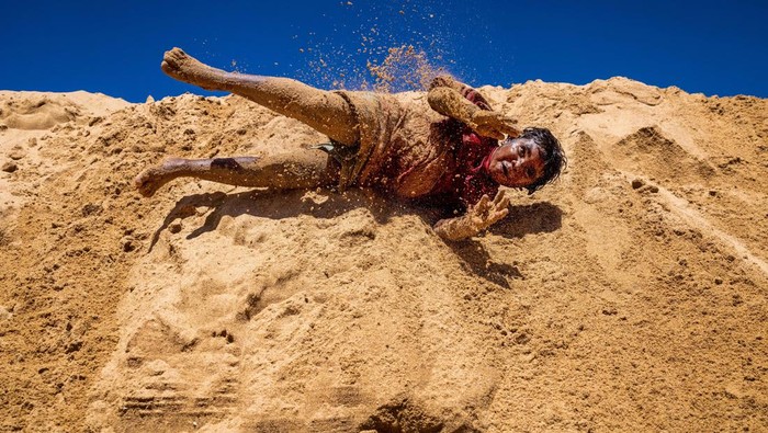SYDNEY, AUSTRALIA - FEBRUARY 03: A boy rolls down sand-hills at North Narrabeen Beach  after a snorkelling lesson with Miss World Australia Kristen Wright on February 3, 2023 in Sydney, Australia. The initiative is part of the Bush to Beach programme, which now in its 18th year, gives indigenous children a unique opportunity to learn and explore Sydney's beach culture. The efforts are made possible entirely by volunteers, donations and sponsorship. Bush to Beach is a charity dedicated to inspiring hope, confidence, self-esteem and promoting education for Aussie bush kids, a release by the charity said. This particular trip is a reward for school attendance and an opportunity for the kids to see that there is another world outside their own community and help develop confidence and self-esteem, according to Bush to Beach co-founder Jack Cannons. (Photo by Jenny Evans/Getty Images)