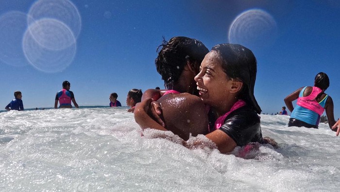 SYDNEY, AUSTRALIA - FEBRUARY 03: A boy rolls down sand-hills at North Narrabeen Beach  after a snorkelling lesson with Miss World Australia Kristen Wright on February 3, 2023 in Sydney, Australia. The initiative is part of the Bush to Beach programme, which now in its 18th year, gives indigenous children a unique opportunity to learn and explore Sydney's beach culture. The efforts are made possible entirely by volunteers, donations and sponsorship. Bush to Beach is a charity dedicated to inspiring hope, confidence, self-esteem and promoting education for Aussie bush kids, a release by the charity said. This particular trip is a reward for school attendance and an opportunity for the kids to see that there is another world outside their own community and help develop confidence and self-esteem, according to Bush to Beach co-founder Jack Cannons. (Photo by Jenny Evans/Getty Images)