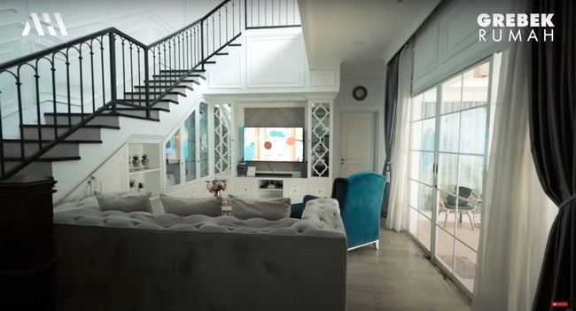 Di sebelah ruang tamu terdapat ruang keluarga yang tak kalah nyaman. Ruang keluarganya itu dilengkapai dengan sebuah sofa panjang berwarna abu-abu, sofa kecil berwarna hijau, dan televisi. Foto: YouTube/AH