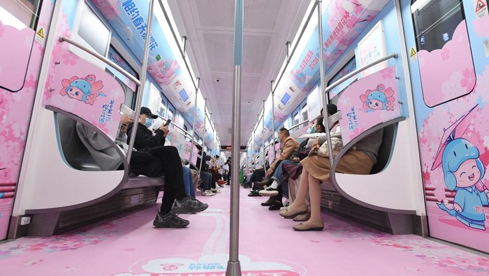WUHAN, CHINA - MARCH 08: Passengers ride a themed subway train with patterns of cherry blossom on March 8, 2023 in Wuhan, Hubei Province of China. With interior and exterior decorated with cherry blossom images, the themed train with operate until April 30. (Photo by VCG/VCG via Getty Images)