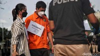 Mario dan Shane menjalani rekonstruksi dengan memakai baju tahanan warna oranye.