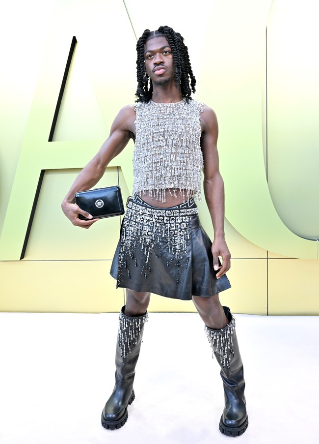 Tren rok di kalangan pria menemani penampilan rapper Lil Nas X di peragaan Versace. Ia memadukannya dengan atasan berkilauan dan boots beraksen embellishment. (Foto: Axelle/Bauer-Griffin/FilmMagic)