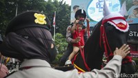 Seorang anak nampak asyik menunggang kuda bersama polisi.