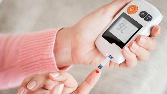 Close up woman hands checking blood sugar level by glucose meter for diabetes tester using as medicine, glycemia, healthcare and medical concept.