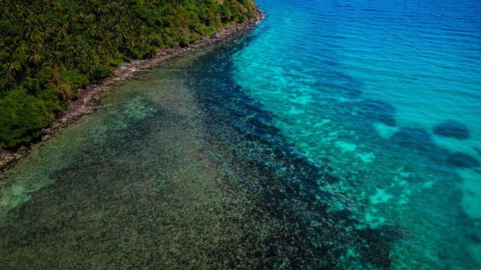 1472121299 POLA, PHILIPPINES - MARCH 08: An aerial view shows oil slick from the sunken tanker MT Princess Empress along a shoreline on March 08, 2023 in Pola, Oriental Mindoro, Philippines. Authorities are racing to contain an oil spill after an oil tanker sunk off the coast of Oriental Mindoro, south of Manila. The tanker, MT Princess Empress, was carrying 800,000 liters of industrial oil when it sank on February 28 due to engine trouble and rough seas. Marine experts estimate that about 36,000 hectares of coral reefs, mangroves, and seagrass are in danger of being damaged. The spill has also prompted authorities to ban fishing and swimming in contaminated waters, halting the livelihood of countless residents who rely on fishing and tourism to survive. (Photo by Ezra Acayan/Getty Images)