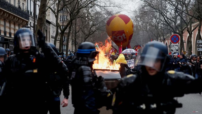 Aksi Bakar Ban Warnai Aksi Tolak Reformasi Pensiun di Prancis Fire burns as French workers on strike gather and block the entry of a fuel depot as they protest against the French government's pension reform plan, in Haulchin, near Valenciennes, France, March 13, 2023. REUTERS/Pascal Rossignol