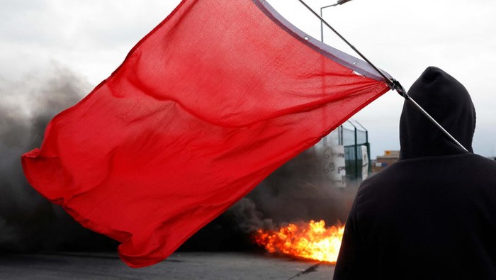 Aksi Bakar Ban Warnai Aksi Tolak Reformasi Pensiun di Prancis Fire burns as French workers on strike gather and block the entry of a fuel depot as they protest against the French government's pension reform plan, in Haulchin, near Valenciennes, France, March 13, 2023. REUTERS/Pascal Rossignol