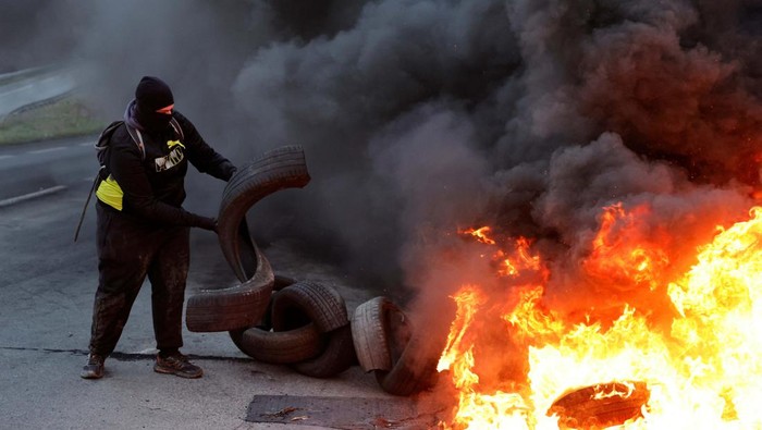 Aksi Bakar Ban Warnai Aksi Tolak Reformasi Pensiun di Prancis Fire burns as French workers on strike gather and block the entry of a fuel depot as they protest against the French government's pension reform plan, in Haulchin, near Valenciennes, France, March 13, 2023. REUTERS/Pascal Rossignol