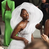 Penyanyi Tems hadir dengan gaun putih bergaya avant-garde yang dilengkapi hiasan dramatis pada bagian punggung. Netizen sempat membicarakan gaun Tems yang menghalangi penonton di belakangnya. Pilihan yang kurang bijak. (Foto: Getty Images)