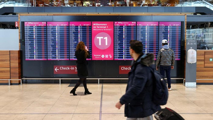 People walk near a departures board, as airport workers protest at BER airport during a strike called by German trade union Verdi, in Berlin, Germany, March 13, 2023. REUTERS/Christian Mang
