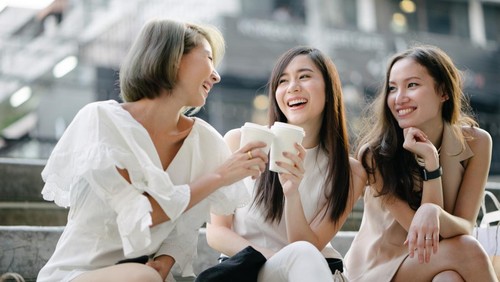 Young beautiful women shopping together, outdoors, smiling, using smartphone