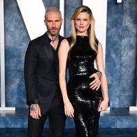 Mereka mencoba menunjukkan keharmonisan pernikahan mereka lewat pilihan busana yang kompak serba hitam. Column dress sequin berkilauan dari Dolce & Gabbana membungkus tubuh ramping sang model. Sementara itu, Adam memilih setelan dengan kancing atas yang dibuka. (Foto: Karwai Tang/WireImage)