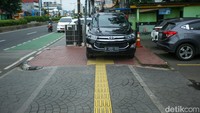 Sebuah mobil parkir di trotoar jalan Otista Raya, Jakarta, Selasa (14/3/2023).  