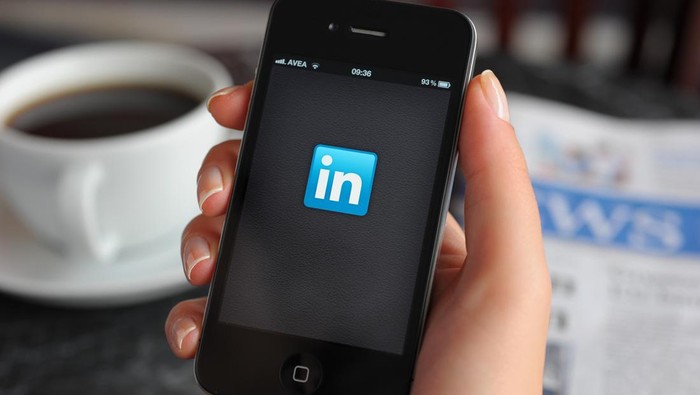 Astanbul, Turkey - December 14, 2011: Woman hand holding an touching an Apple iPhone 4 in a coffee shop. iPhone 4 displaying start up screen of LinkedIn application. The iPhone 4 is a touchscreen slate smartphone and the fourth generation iPhone, developed by Apple Inc.