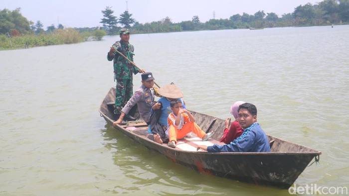 Warga menaiki perahu karena permukiman Desa Banjarsari Kecamatan Gabus kebanjiran. Selain itu warga juga diperiksa kesehatannya, Rabu (15/3/2023).